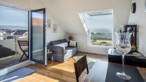 A modern loft apartment with a large skylight, a sofa, a dining table, and a view of the city. - Sankt Bernhard Apartment for 3 Guests (Wasserburg (Bodensee))