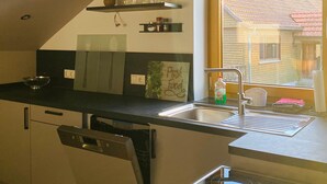 Una cocina moderna con lavavajillas integrado, un lavamanos de acero inoxidable y una ventana con vistas a una zona residencial.
