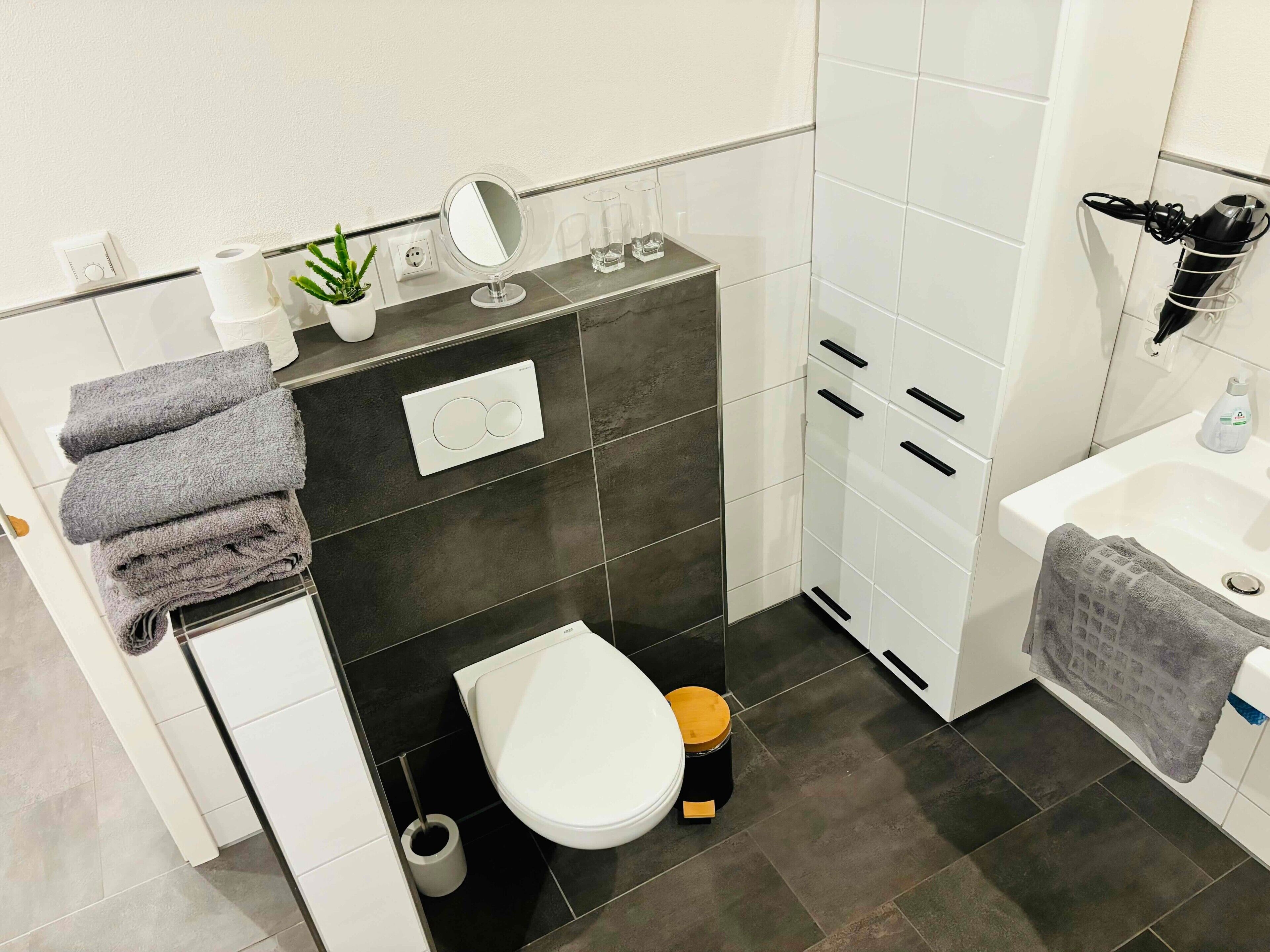 Une salle de bain moderne équipée de toilettes, d’un lavabo et de meubles de rangement.