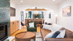 Un salon moderne avec une cheminée, un coin repas et une cuisine en arrière-plan.