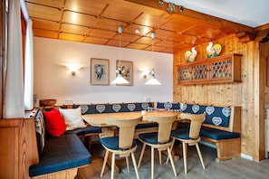 A wooden interior with a long bench, table, and chairs.