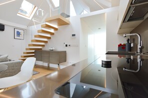 A modern kitchen with a glass countertop, a wooden staircase, and a minimalist design. - Soho Penthouse by Concept Apartments (London)