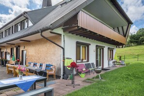 Une maison dotée d’un patio, d’un espace salon extérieur et d’un petit jardin.