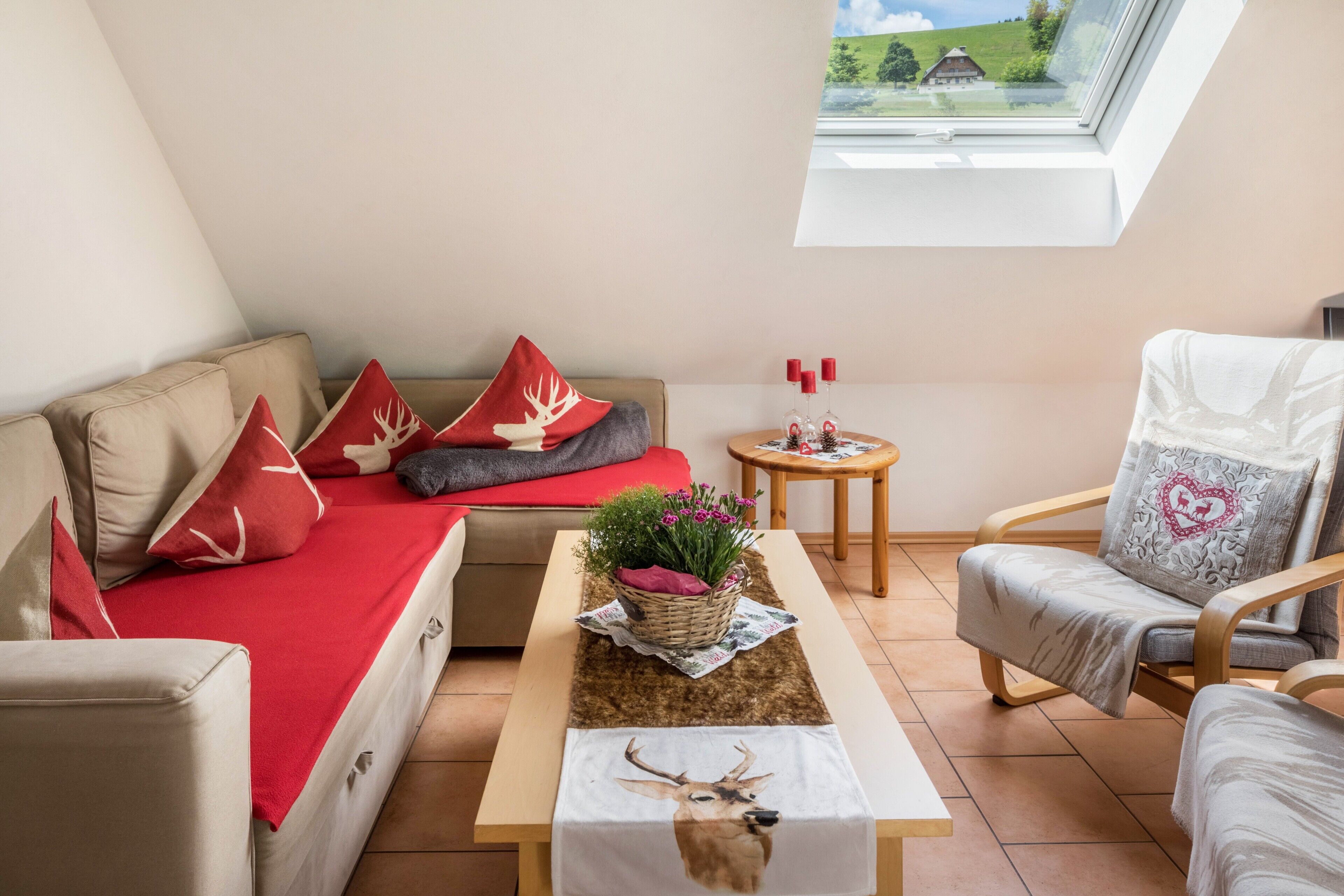 Een gezellige kamer met een bank, fauteuil en een tafel met een bloemenmand.