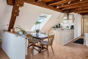A kitchen with wooden beams, a dining table with chairs, a window, and a kitchen island. - Apartment 'Sport Rees - Pia' with Mountain View, Shared Terrace & Wi-Fi (Oberried-Hofsgrund)