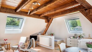 Una camera da letto mansardata accogliente, con travi in legno, un lucernario, una scrivania, una sedia, un letto e una cassettiera.
