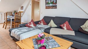 A modern living room with a sofa, a dining table, and a coffee table. - Holiday Apartment 'Anna' with Mountain View, Shared Terrace and Wi-Fi (Oberried-Hofsgrund)