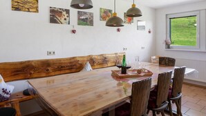 A dining area with a wooden table, chairs, pendant lights, and artwork on the walls. - Apartment 'Sport Rees - Stefanie' with Mountain View, Shared Terrace & Wi-Fi (Oberried-Hofsgrund)
