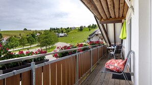 A balcony with a view of a green landscape, a wooden ceiling, and a chair with a cushion. - Apartment 'Sport Rees - Stefanie' with Mountain View, Shared Terrace & Wi-Fi (Oberried-Hofsgrund)
