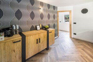 A modern kitchen with a patterned wallpaper, wooden cabinets, and a herringbone floor. - Vacation home Haus Waldberg with large garden and covered veranda (Unterschönau)