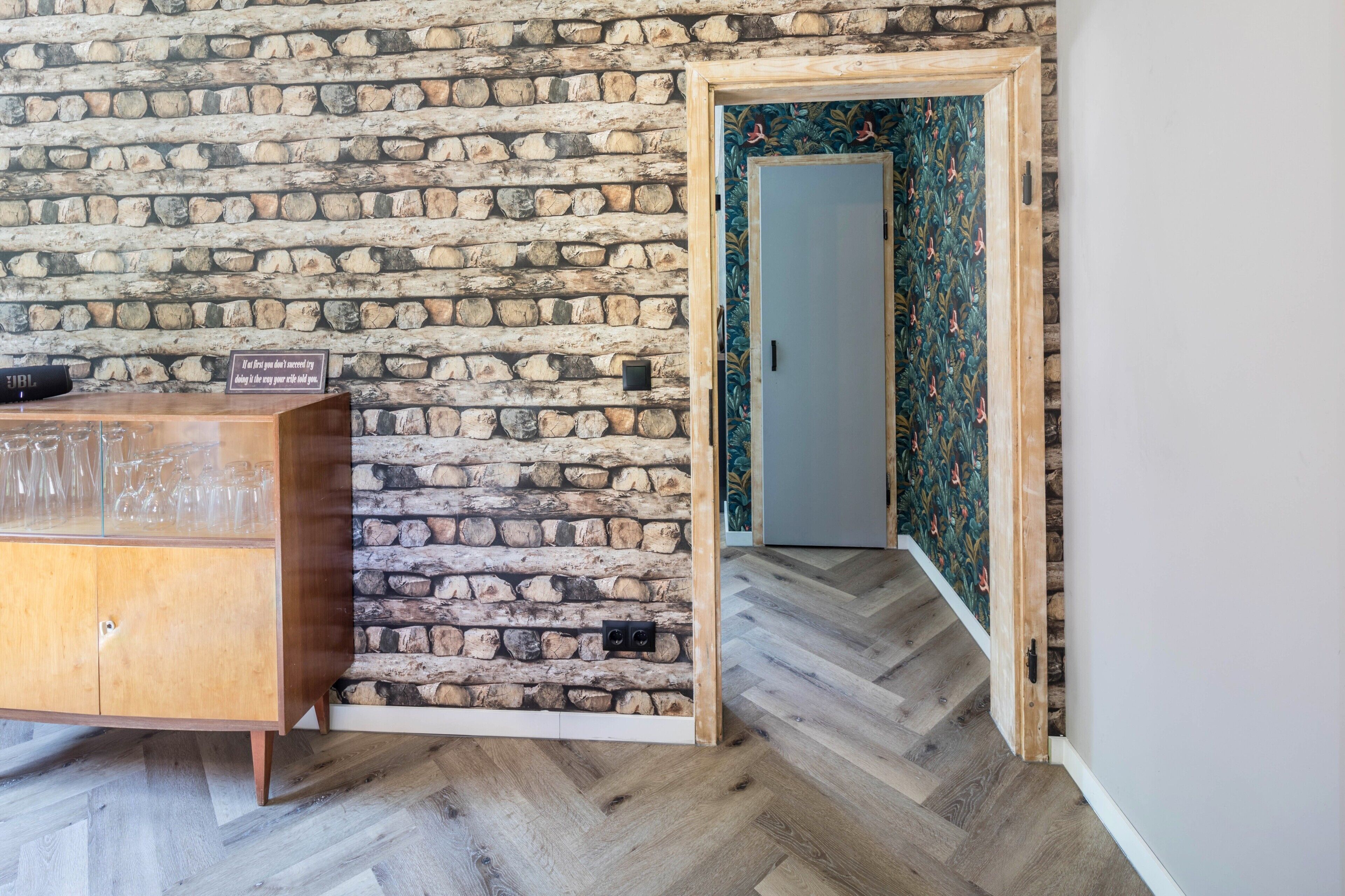 A room with a stone wall, a wooden cabinet, and a door with floral wallpaper.