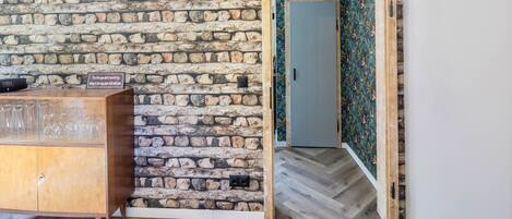 A room with a stone wall, a wooden cabinet, and a door with floral wallpaper.