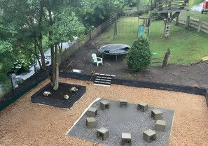 Un parque infantil con un trampolín, columpios y un tobogán.
