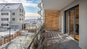 Un apartamento moderno con balcón, una puerta de madera y vistas a edificios vecinos.
