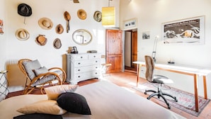 A bedroom with a bed, a dresser, a chair, a desk, and a wall with hats and a poster. - Tuscan Home Panoramic Hills Private Terrace (Rignano sull'Arno)