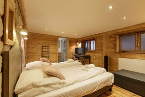 Ein Schlafzimmer einer Holzhütte mit zwei Betten, einem Fernseher und einem kleinen Schreibtisch.