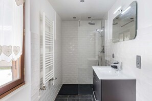 Ein Badezimmer mit Dusche, Waschbecken und Spiegel.