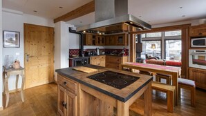 Una cocina moderna con armarios de madera, una isla central con estufa y un ventanal con vistas al exterior.