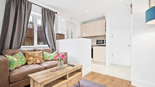 A compact living space with a sofa, a coffee table, and a kitchen area.