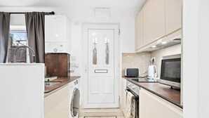 A compact kitchen with a washing machine, a microwave, and a toaster.