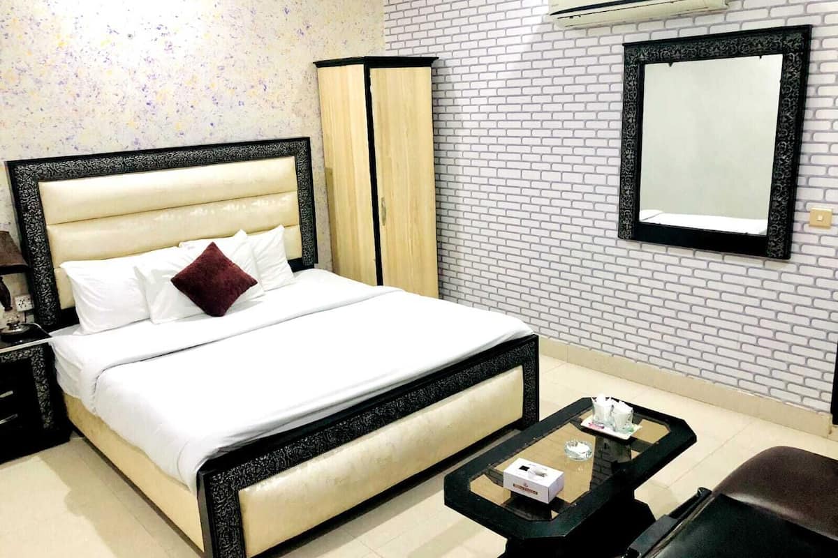 Ein Hotelzimmer mit Bett, Nachttisch, Schreibtisch, Stuhl, Spiegel und einer Wand mit Ziegelmuster.