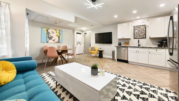 A modern living room with a blue sofa, a white coffee table, and a patterned rug.