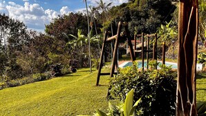 Un jardín bien cuidado con piscina, rodeado de abundante vegetación y una pérgola de madera.
