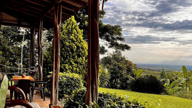 Un espacio de estar al aire libre cubierto con vistas a un paisaje exuberante.