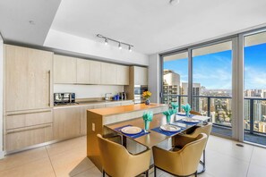 A modern kitchen with a dining area, large windows, and a city view. - Phenomenal 2 Bedroom Corner Ocean View Stay (Hollywood)