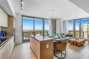 A modern apartment with a kitchen, dining area, and living space with large windows offering city views.