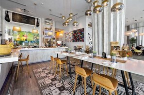 A modern restaurant with a bar area, high ceilings, and pendant lighting.