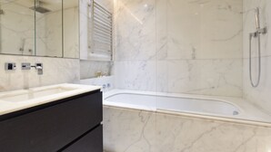 Une salle de bain moderne avec un lavabo en marbre, une baignoire et une cabine de douche en verre.