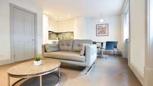 Un salon moderne avec une table basse ronde, un canapé beige et un coin repas comprenant une table et des chaises.