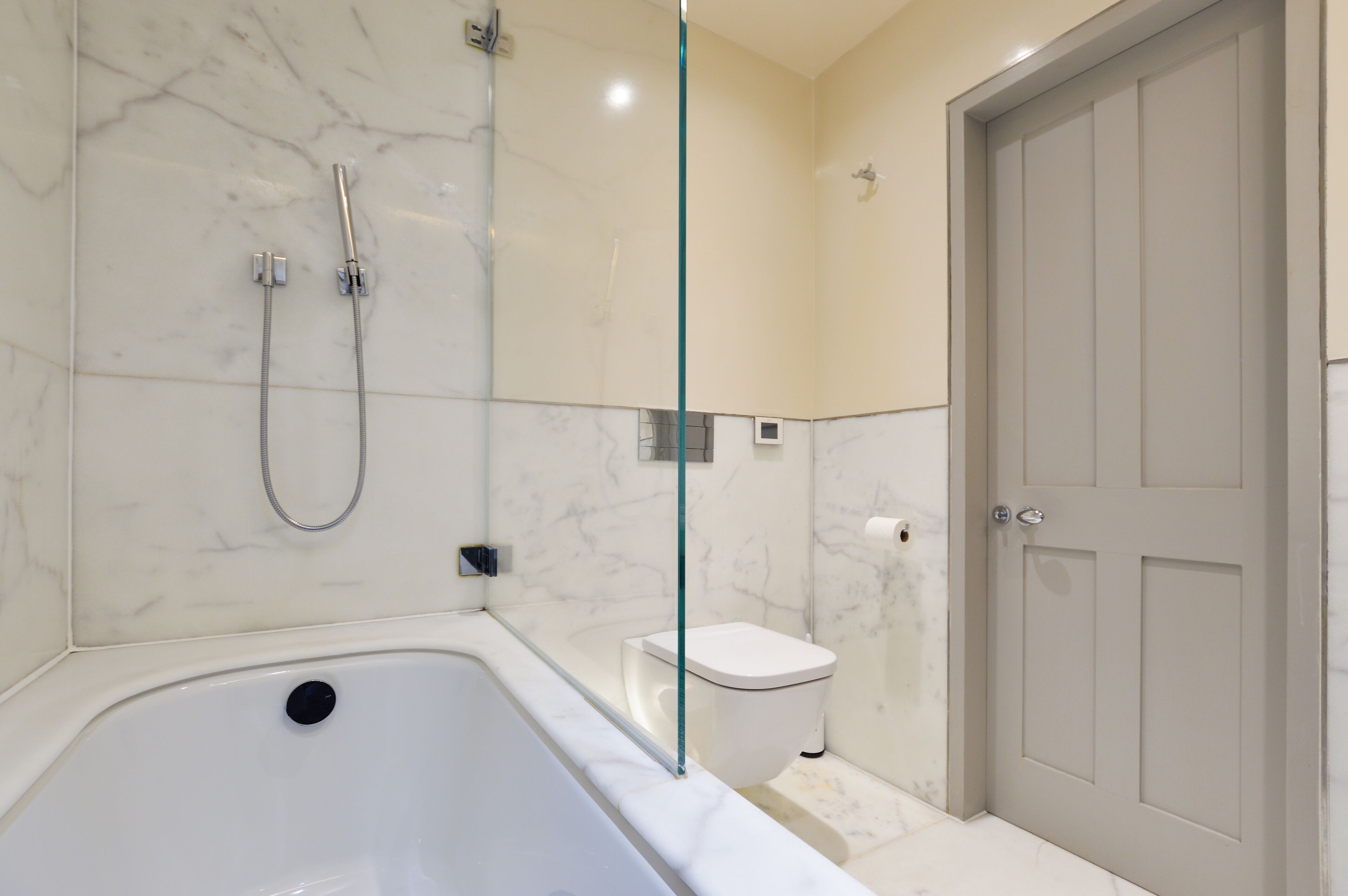 Een moderne badkamer met een badkuip, een douche met glazen wanden en een toilet.