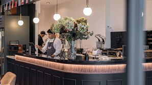 A modern bar area with a dark counter, hanging pendant lights, and a large floral arrangement.