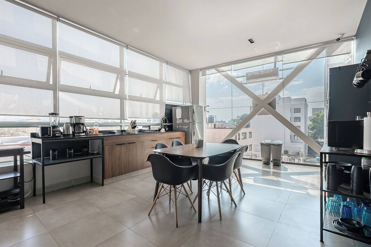 A modern kitchen with large windows, a dining area with chairs, and a view of the city.