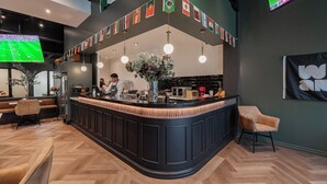 A modern bar area with a curved counter, flags, and a TV screen.