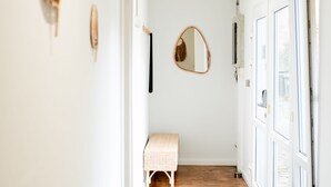 A narrow hallway with white walls, wooden flooring, and a bench. There are framed items on the walls and a round mirror. - Hamburg - 3 Rooms for up to 11 guests (Hamburg)
