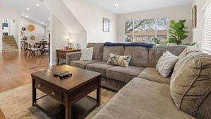 A modern living room with a sectional sofa, a coffee table, and a dining area with chairs and a table.