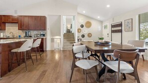 A modern kitchen with wooden cabinets, a bar area, and a dining space with a large wooden table and chairs.