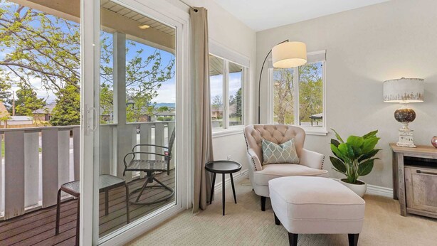 A balcony with a cushioned seating area, a small table, and a potted plant.