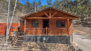 A cabin with a wooden exterior, stone foundation, and a porch with a railing.