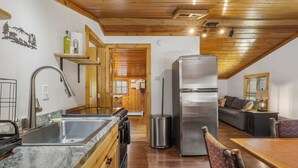 A modern kitchen with a stainless steel refrigerator, wooden cabinets, and a granite countertop. - Cabin 10- King Cabin, Mins to RMNP! (Estes Park)