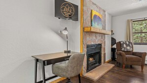 Un salon moderne avec une cheminée, un bureau et un fauteuil confortable.