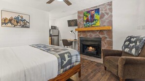 Een slaapkamer met een bed, een stoel, een open haard en een bureau.