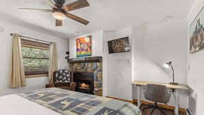 A bedroom with a bed, a fireplace, a desk, and a chair. - Cabin 18 - King Bed, Mountain views! Hotel Style! (Estes Park)
