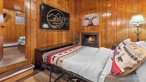 Ein Zimmer mit Holzwänden, einem Bett, einem Kamin und einem angebrachten Schild mit der Aufschrift 'Elevate bnb'.