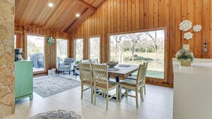 A wooden-paneled dining room with a large table and chairs, a green cabinet, and a view of the outdoors. - Hot Tub, Deck & Grill: Brookshire Gem Near Venues (Brookshire)
