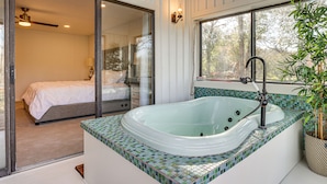 A modern bathroom with a glass-enclosed shower, a freestanding bathtub, and a large window offering a view of the outdoors. - Hot Tub, Deck & Grill: Brookshire Gem Near Venues (Brookshire)