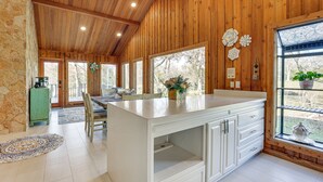 A spacious kitchen with wooden walls, large windows, and a central island. - Hot Tub, Deck & Grill: Brookshire Gem Near Venues (Brookshire)
